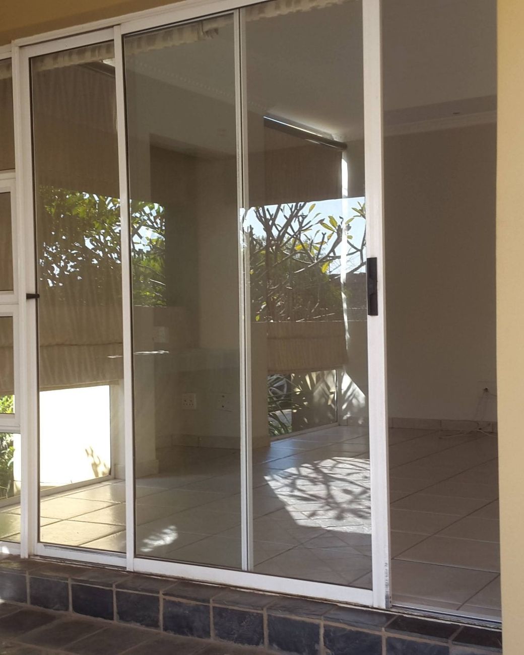 White aluminium sliding doors and windows opening onto a tiled patio