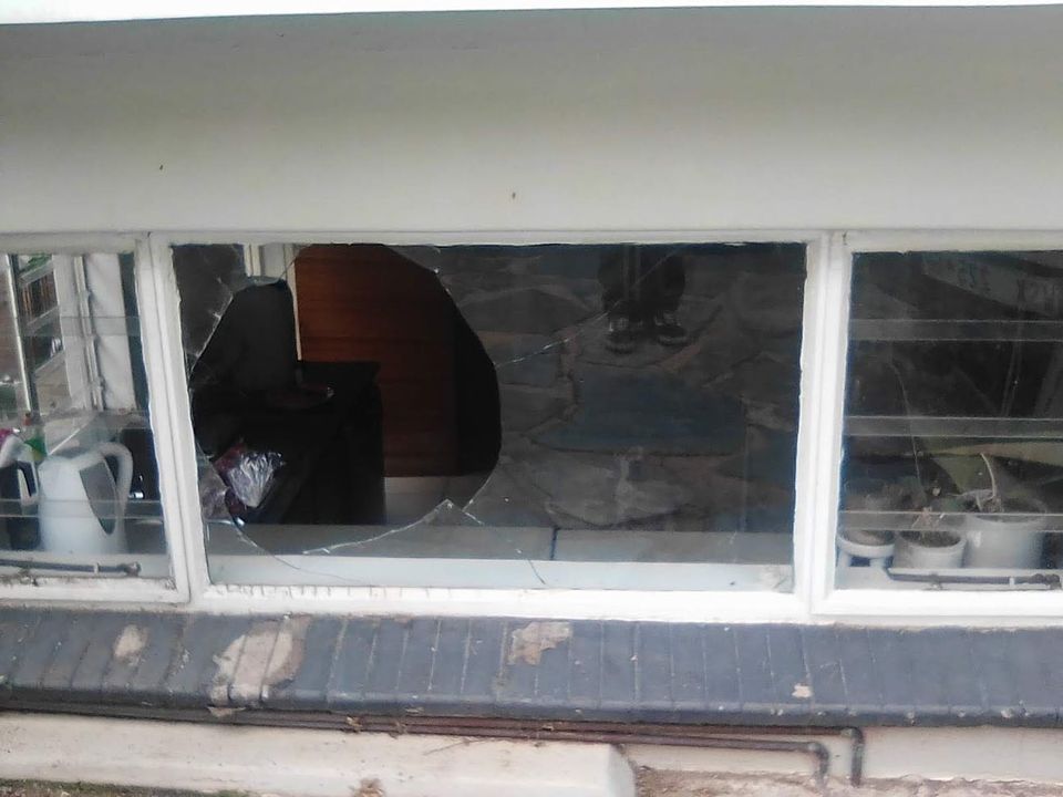 A long window with a large hole broken through the middle pane