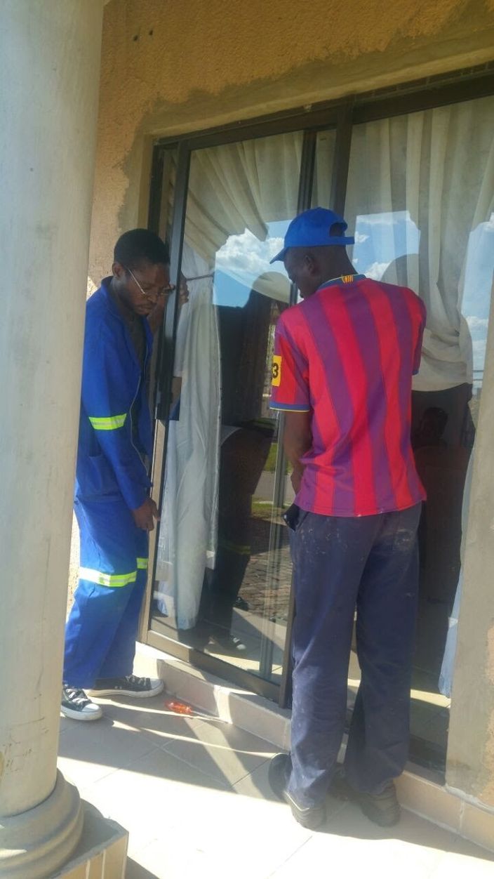 Two people working on a sliding door frame