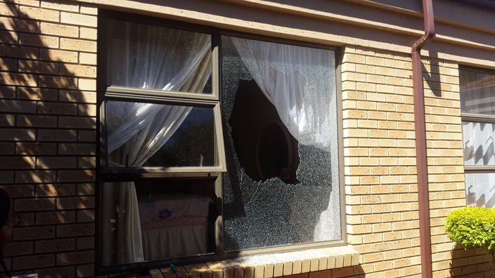 A shattered pane in a window of a face-brick house, waiting to be replaced